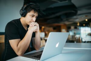 guy with headphones looking at laptop while studying on his learning management platforms